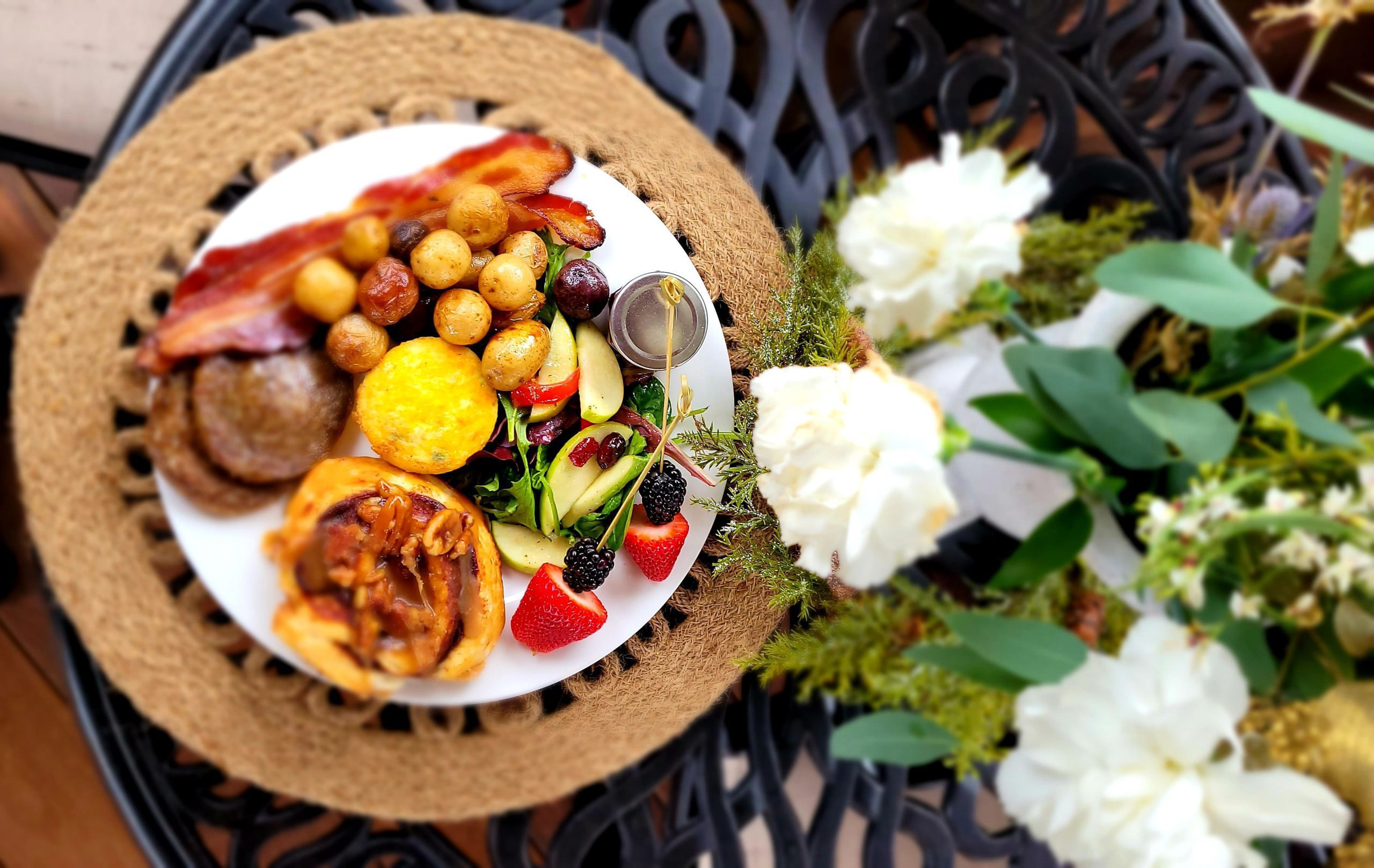 Delicious plate of food with white flower bouquet beside it