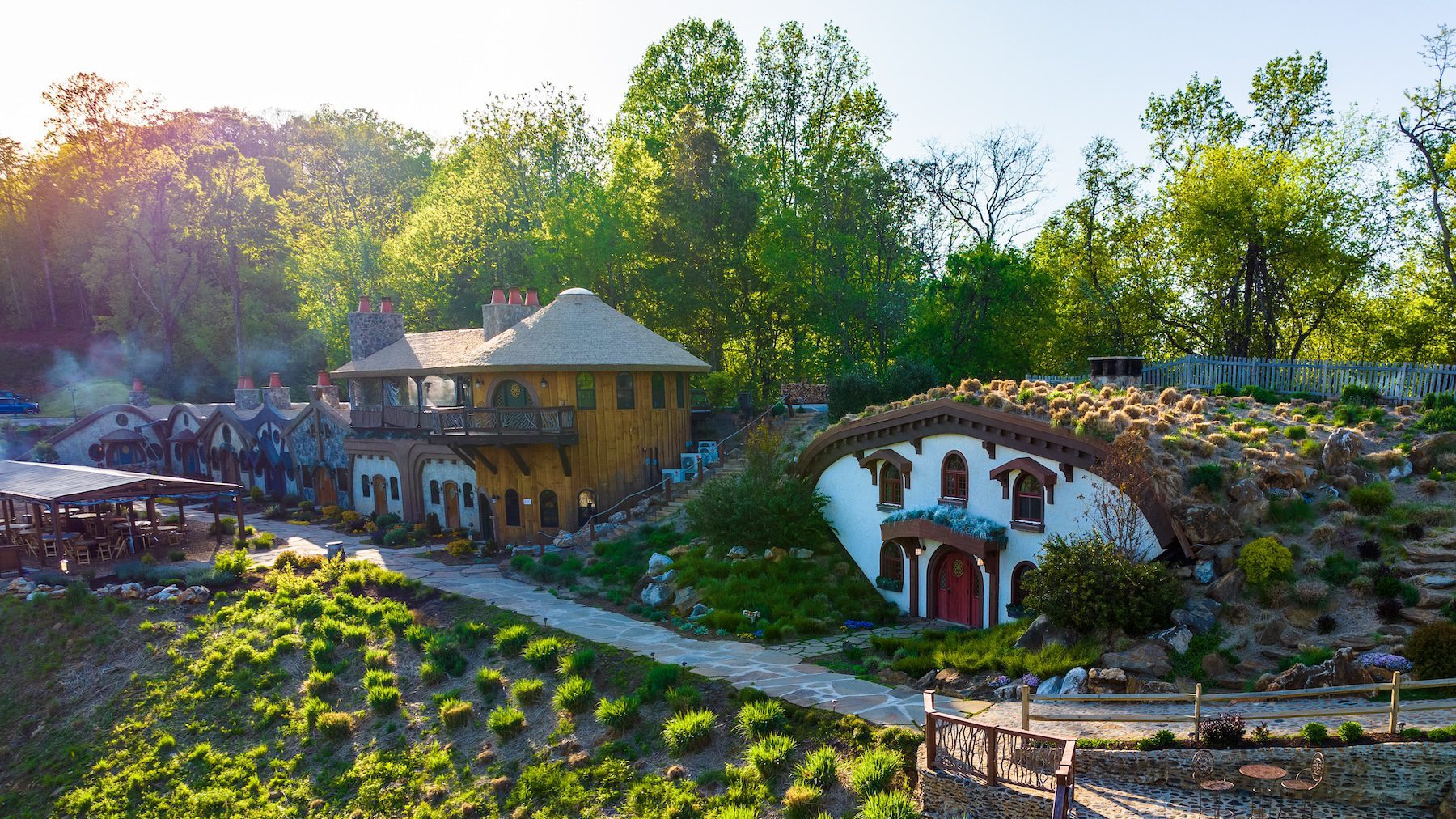 A scenic village with hobbit-style houses nestled among greenery, featuring winding paths and lush surroundings.