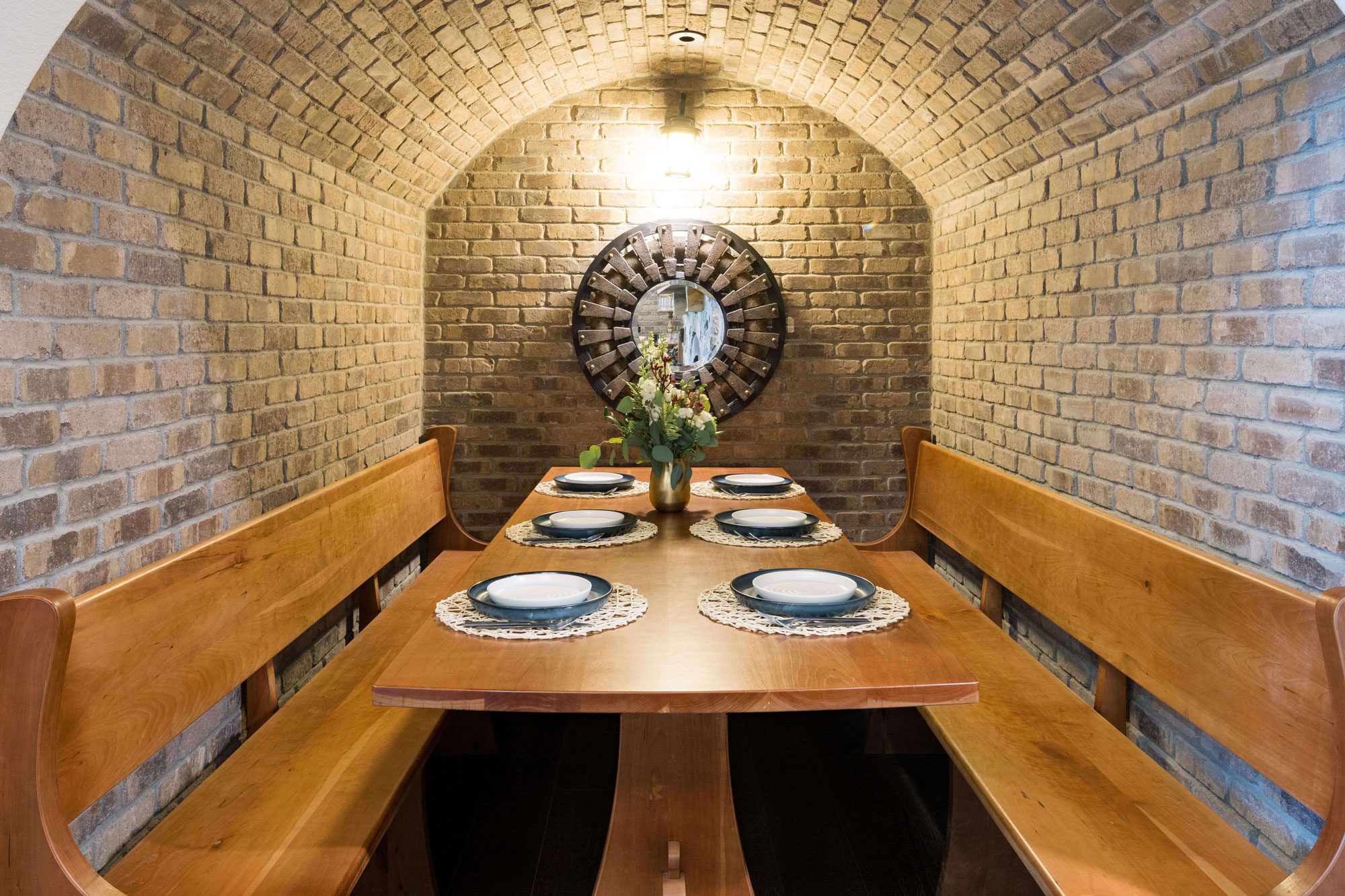 a wooden table set for dinner in a room with brick walls
