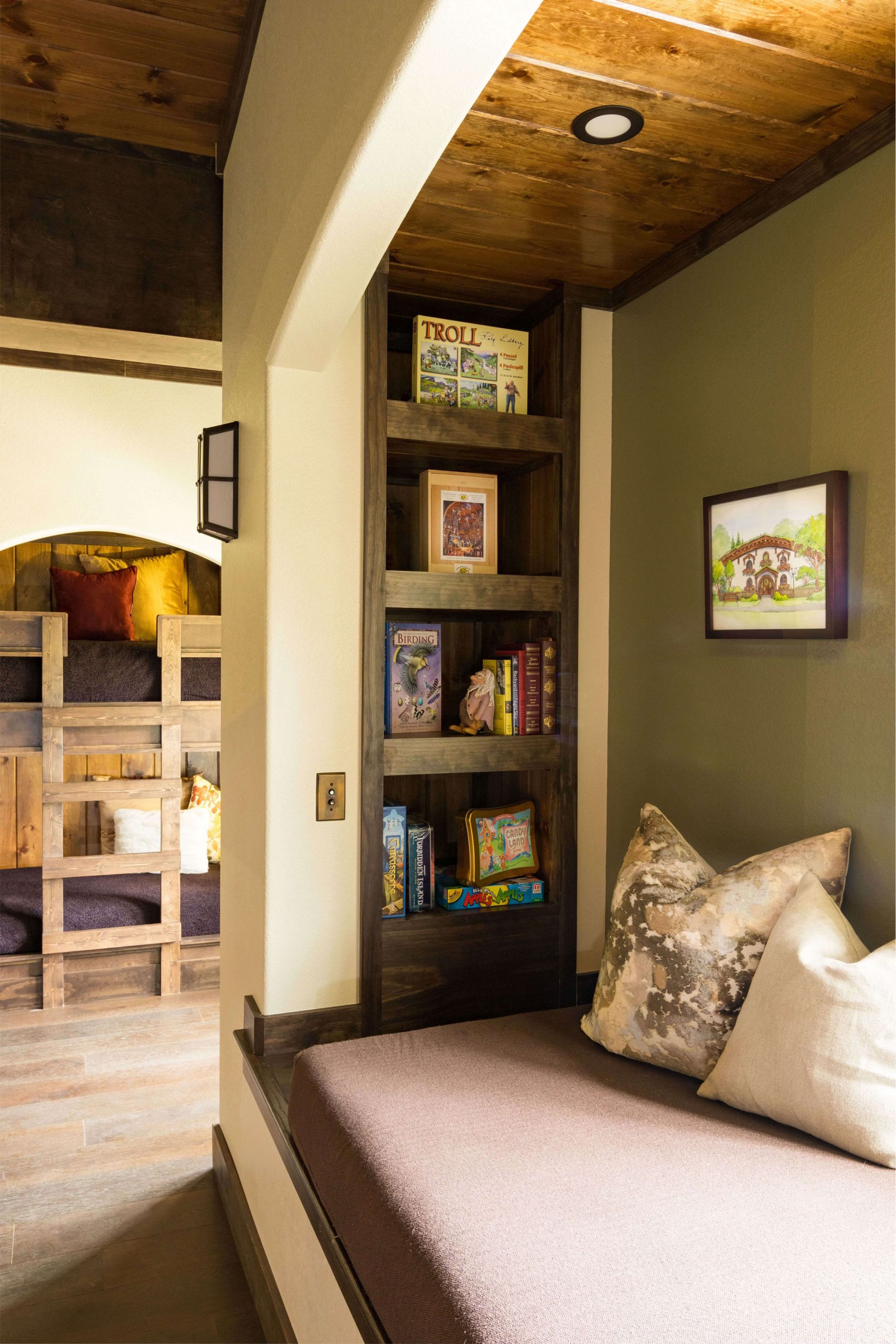 a daybed beside a bookshelf filled with games and books for the family to enjoy while staying overnight